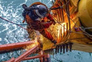 Técnico IRATA realizando una soldadura en una plataforma petrolífera.