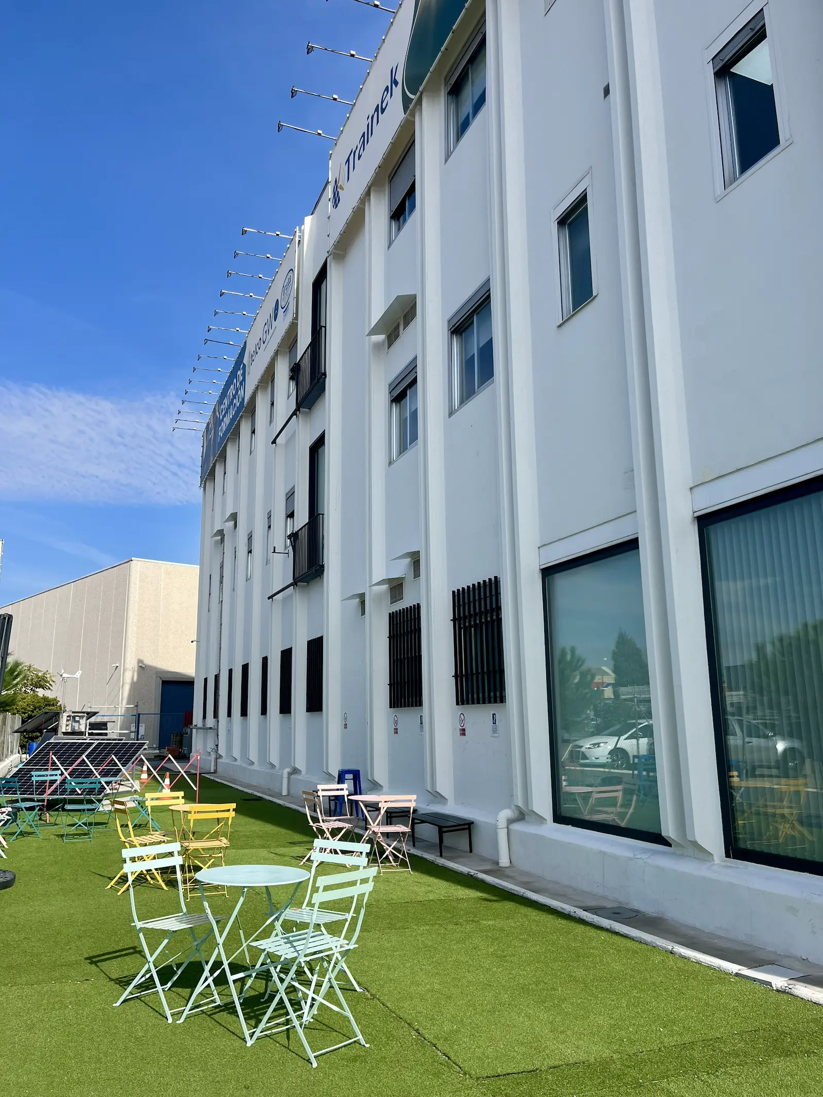 Zona de descanso exterior con mesas junto a las placas solares de Trainek