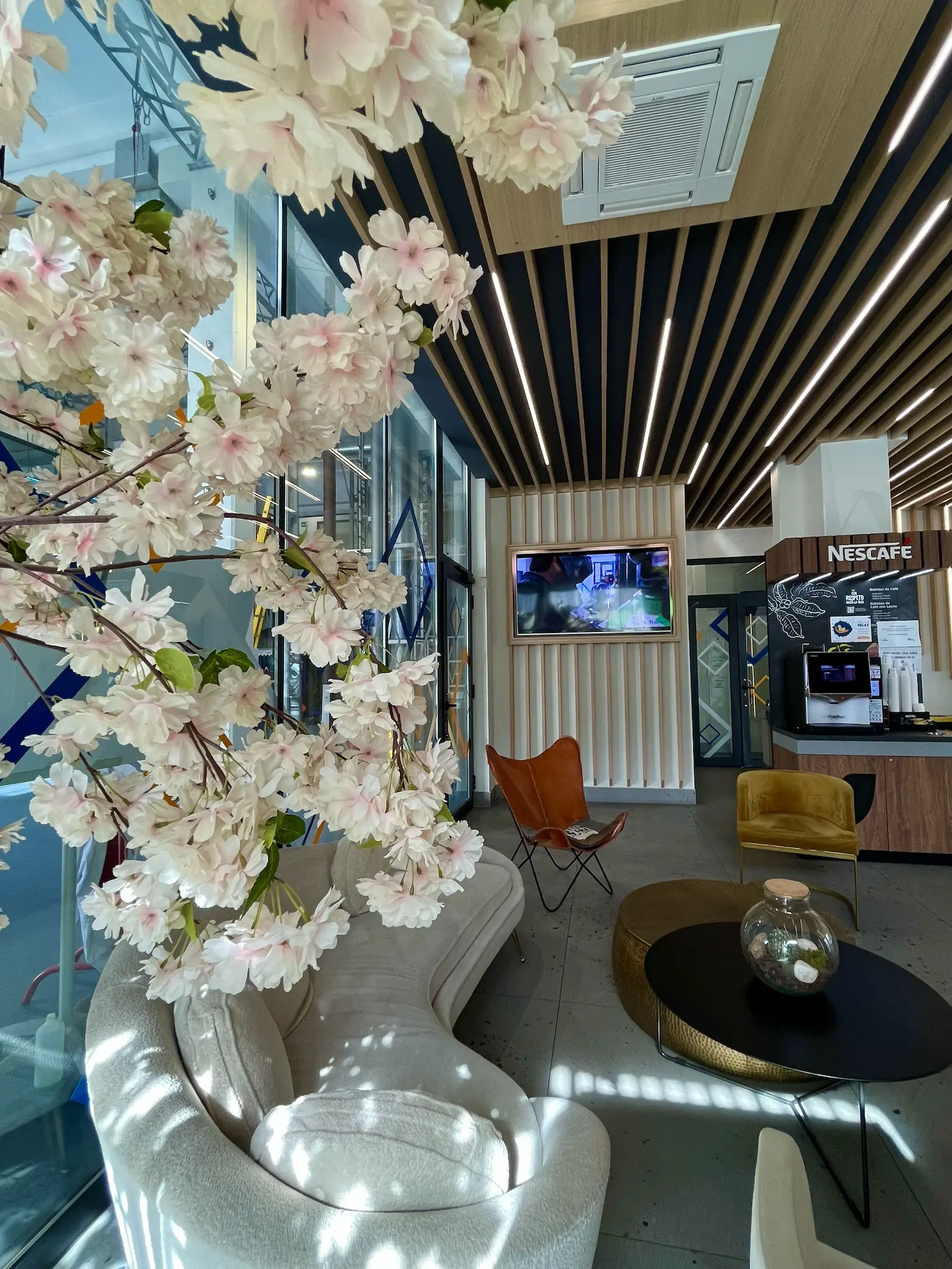 Hall de Trainek decorado con un árbol de flores blancas y pantallas informativas